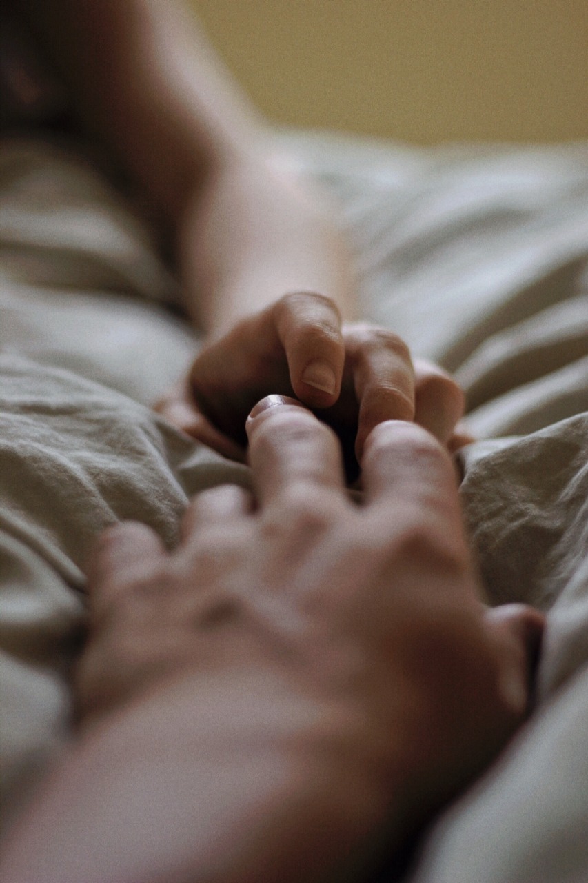 Сую пальцы спящей. Руки влюбленных. Утренние объятия. Нежные объятия в постели. Рука на кровати.